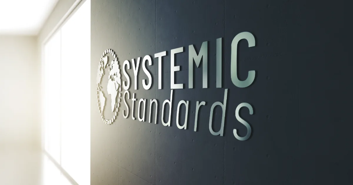 Systemic Standards company logo with 3D effect on a modern office wall